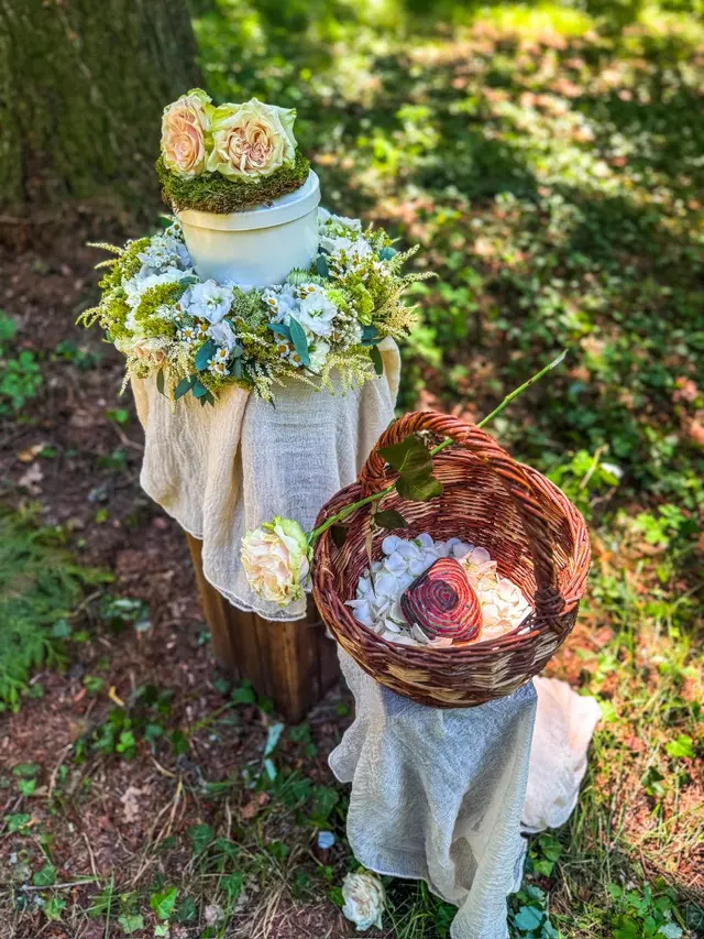 Urne mit Blumenschmuck bei einer Aufbahrung im Friedwald