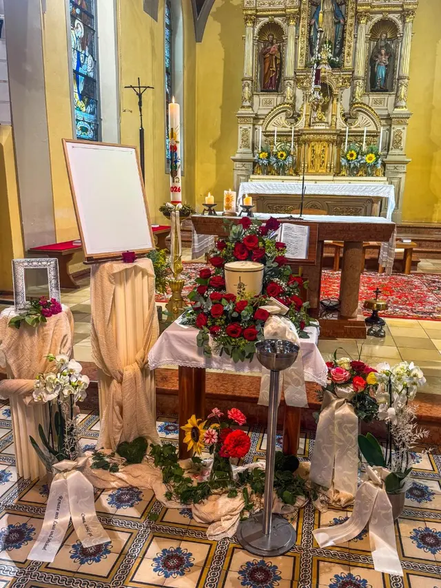 Würdevolle Aufbahrung mit Urne und roten Rosen vor dem Hochaltar einer Kirche