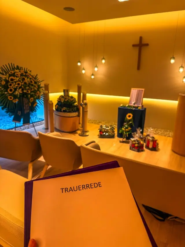 Trauerfeier mit Trauerrede, Urne und Sonnenblumenkranz in einer modernen Kapelle